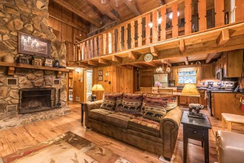 a living room with a couch and a stone fireplace at Authentic log home with hot tub, fireplace, fire pit and billiards ! in Gatlinburg