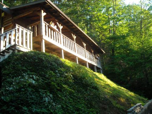a large wooden house on a hill in the woods at Authentic log home with hot tub, fireplace, fire pit and billiards ! in Gatlinburg