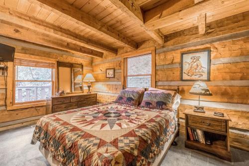 a bedroom with a bed in a room with wooden walls at Authentic log home with hot tub, fireplace, fire pit and billiards ! in Gatlinburg