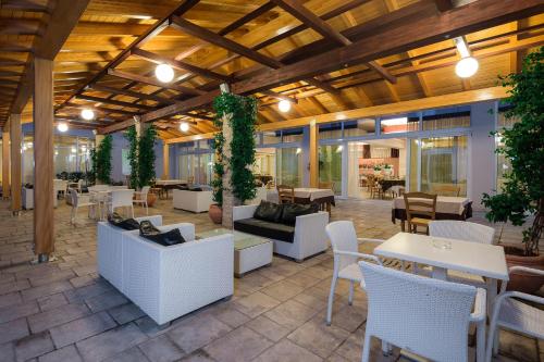 a patio with white furniture and tables and plants at Medjugorje Hotel & Spa in Međugorje