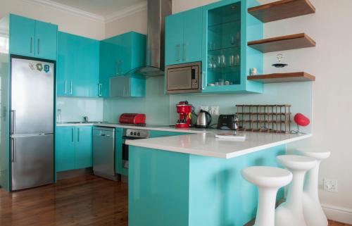 cocina con armarios azules y encimera blanca en Harbour Views, en Kalk Bay