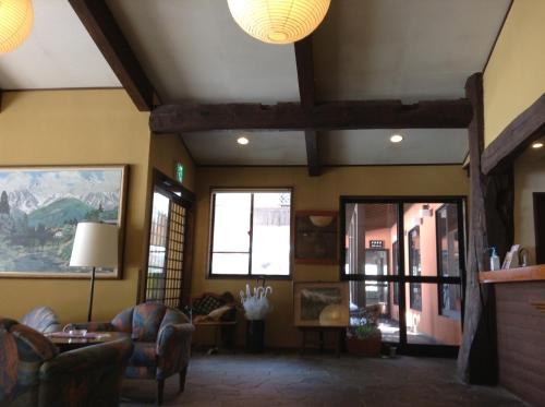 a living room with couches and windows at Hakuba Alpine Hotel in Hakuba