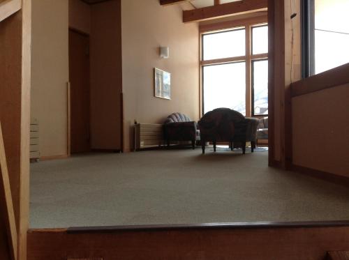 an empty room with a chair and windows at Hakuba Alpine Hotel in Hakuba