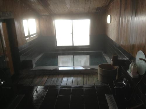 a bath tub in a room with a window at Hakuba Alpine Hotel in Hakuba