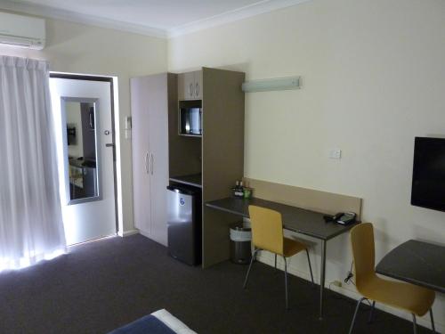 a room with a desk and a table and chairs at Caravilla Motor Inn in Taree