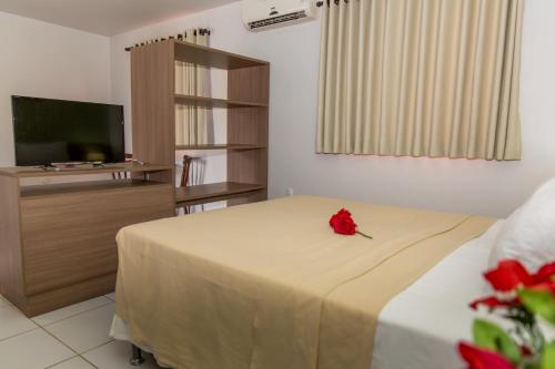 Un dormitorio con una cama con una rosa roja. en Pousada Villamor - Naturista Liberal (Adult Only), en Jacumã