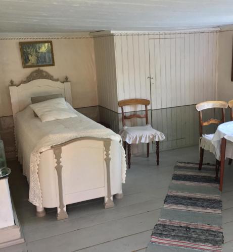 a bedroom with a white bed and two chairs at Thorstorps Gård B&B in Söderköping