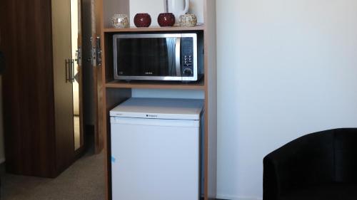 a microwave sitting on a shelf next to a refrigerator at Trivelles Mayfair,stockport in Manchester