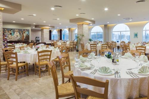 a dining room with white tables and chairs at Medjugorje Hotel & Spa in Međugorje