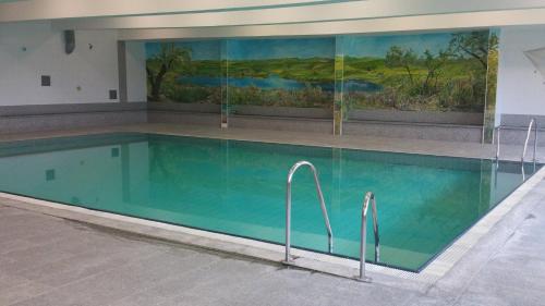ein Pool in einem Gebäude mit einem Gemälde an der Wand in der Unterkunft Hotel Reuterhof in Reuterstadt Stavenhagen