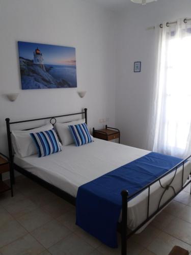 a bedroom with a bed with blue sheets and a window at Kapetan Giannis in Adamas