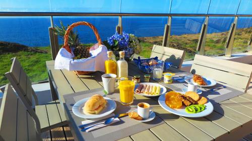a table with plates of food on it with a view of the ocean at Sao Vicente Lodge - Atlantic Retreat in São Vicente Ferreira