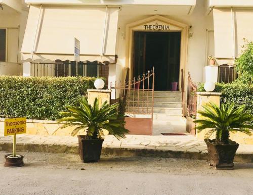 a building with two potted plants in front of a door at Theoxenia Paralio Astros in Paralio Astros