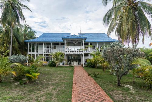 a large white house with a blue roof and palm trees at Quinta del Mar Tintipán in Isla Mucura