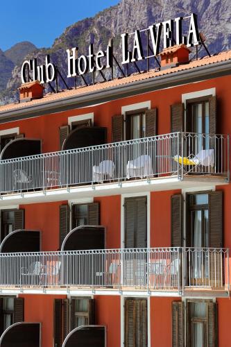 an orange hotel with white balconies and a sign on it at Club Hotel e Residence La Vela in Nago-Torbole