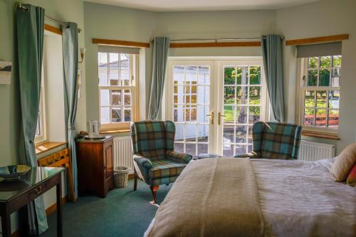 a bedroom with a bed and two chairs and windows at Claremont Cottage in St. Andrews