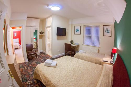 a hotel room with two beds and a television at Gatwick Turret Guest House in Horley