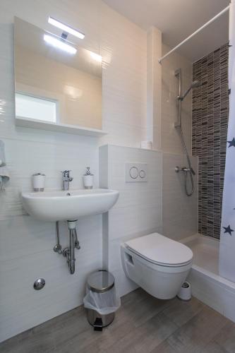 a white bathroom with a sink and a toilet at The Little Prince in Lopud Island