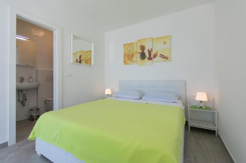 a white bedroom with a green bed and a bathroom at The Little Prince in Lopud Island