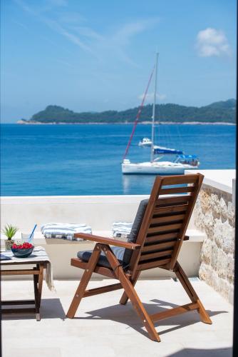 a wooden chair sitting next to a table and a boat at The Little Prince in Lopud Island