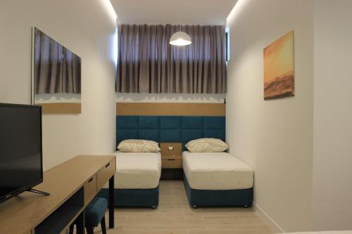 a room with two beds and a desk and a tv at Domus Hotel & Apartments in Shëngjin