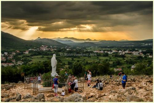 a group of people standing around a statue on a hill at Medjugorje Hotel & Spa in Međugorje