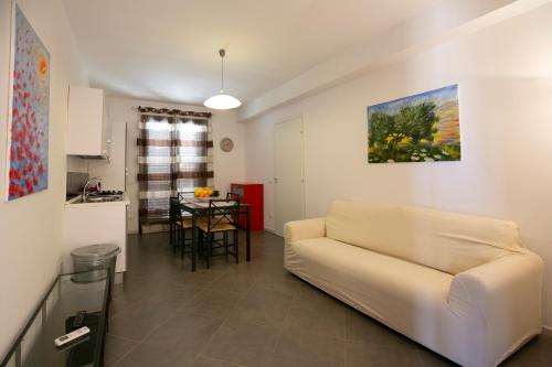 a living room with a white couch and a kitchen at Boa Vista San Vito - Area Fitness, Barbecue Area, Tennis Court in San Vito lo Capo