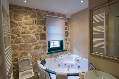 a bathroom with a tub and a toilet and a window at Hotel Arhontiko Vourloka in Pramanta