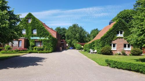 a house covered in ivy next to a driveway at Gästehaus Zur alten Post in Dornumersiel