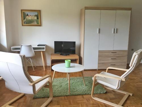 salon z 2 krzesłami, stołem i telewizorem w obiekcie Gostisce Sobocan w Mariborze