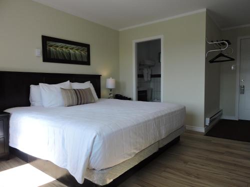a bedroom with a large bed with white sheets at Almo Court Motel in Cranbrook