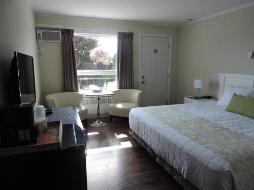a bedroom with a bed and a desk and a window at Almo Court Motel in Cranbrook
