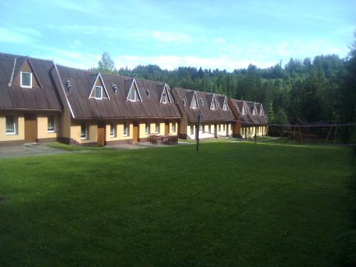 a row of houses with a green lawn in front of it at Ośrodek Wczasowy "GRONOSTAJ" in Rajcza