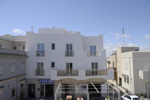 a white building in the middle of some buildings at Hotel Morini in San Foca