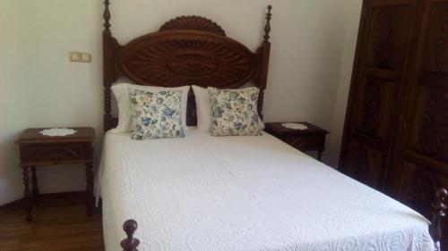 a bedroom with a bed with a wooden headboard and pillows at Pensao Avenida in Caldelas