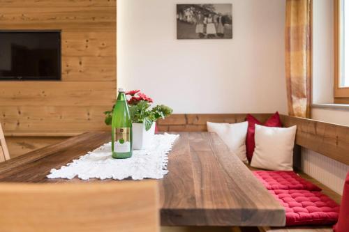 a table with a bottle of wine and flowers on it at Bachmannhof in Feldthurns
