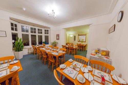uma sala de jantar com mesas e cadeiras de madeira em Gatwick Turret Guest House em Horley