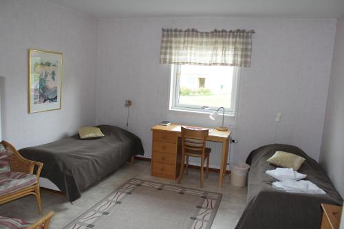 a bedroom with two beds and a desk and a window at Liljeholmen Herrgård Hostel in Rimforsa