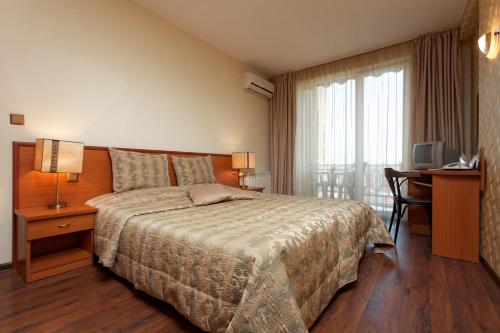 a bedroom with a bed and a desk and a television at Hotel Kabakum in Golden Sands