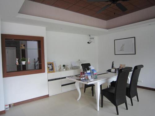 a dining room with a white table and black chairs at White Cat Hotel in Khao Lak