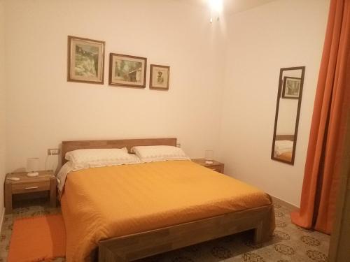 una camera da letto con un letto con lenzuola arancioni e due tavoli di I tre scalini a Stintino