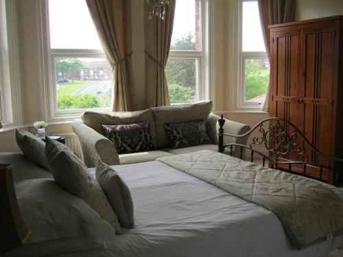 a bedroom with a bed and a couch and windows at Autumn Leaves Guest House in Whitby