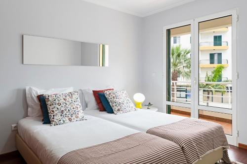 una camera bianca con un grande letto con finestra di Piornais I by An Island Apart a Funchal