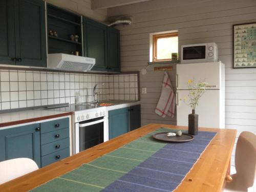 a kitchen with green cabinets and a wooden table at Brissund in Visby