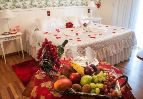 a tray of fruit on a table in front of a bed at Pousada das Hortênsias in Campos do Jordão