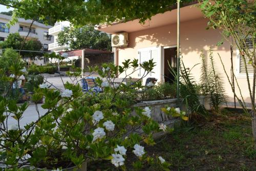 a garden with white flowers in front of a house at Apartment S&M in Tivat