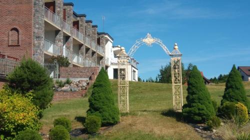 an arch in front of a building with trees at Dom Wczasowy Stenka in Gowidlino