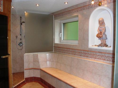 a bathroom with a tub with a statue of a woman at Hotel garni Landhaus Bürtlmair in Hinterstoder