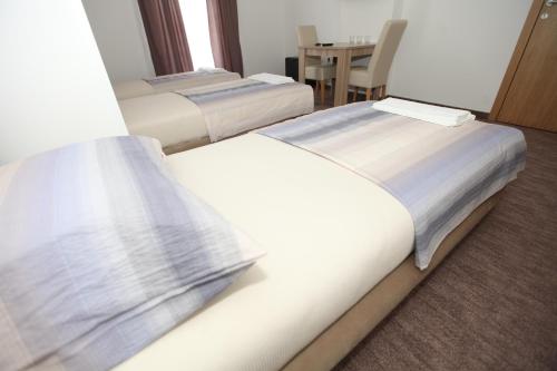 two beds in a hotel room with a table at Ninkovic in Trebinje