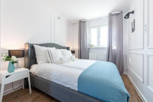 a bedroom with a bed with a blue blanket and a window at P&O Apartments Emilii Plater in Warsaw